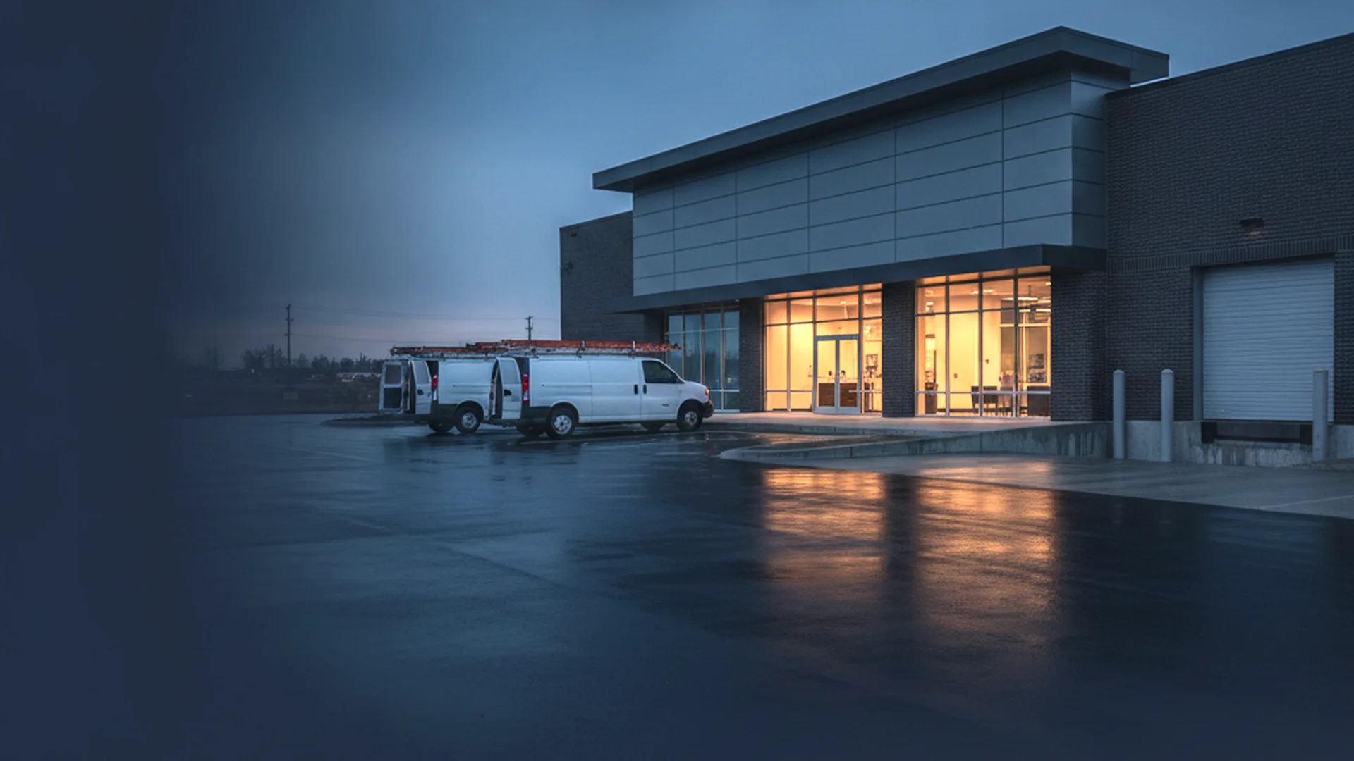 Contractor vans at the service entrance of a commercial building at dusk